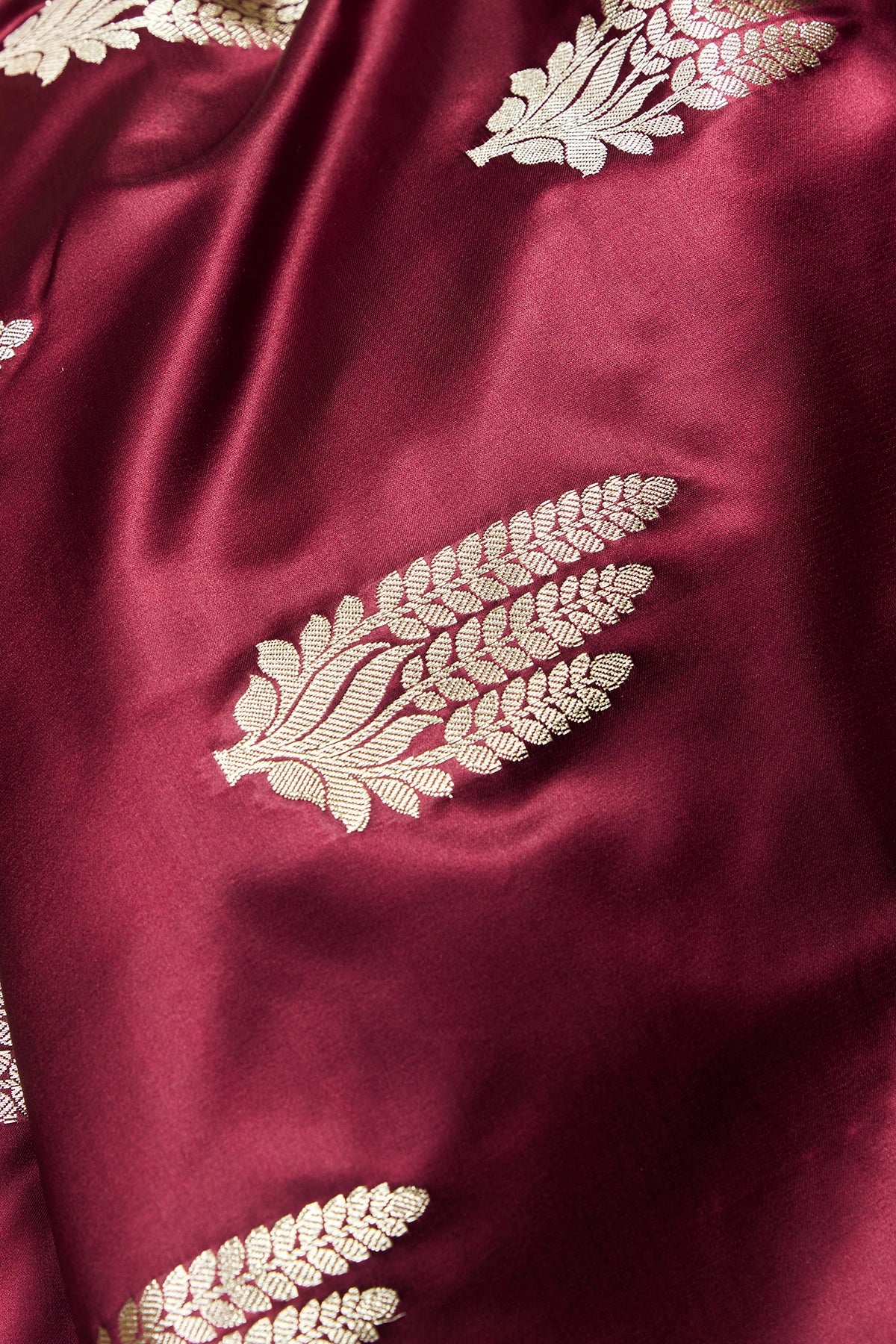 Detailed view of golden floral booti motifs woven across the body of the maroon Banarasi Mashru silk saree.