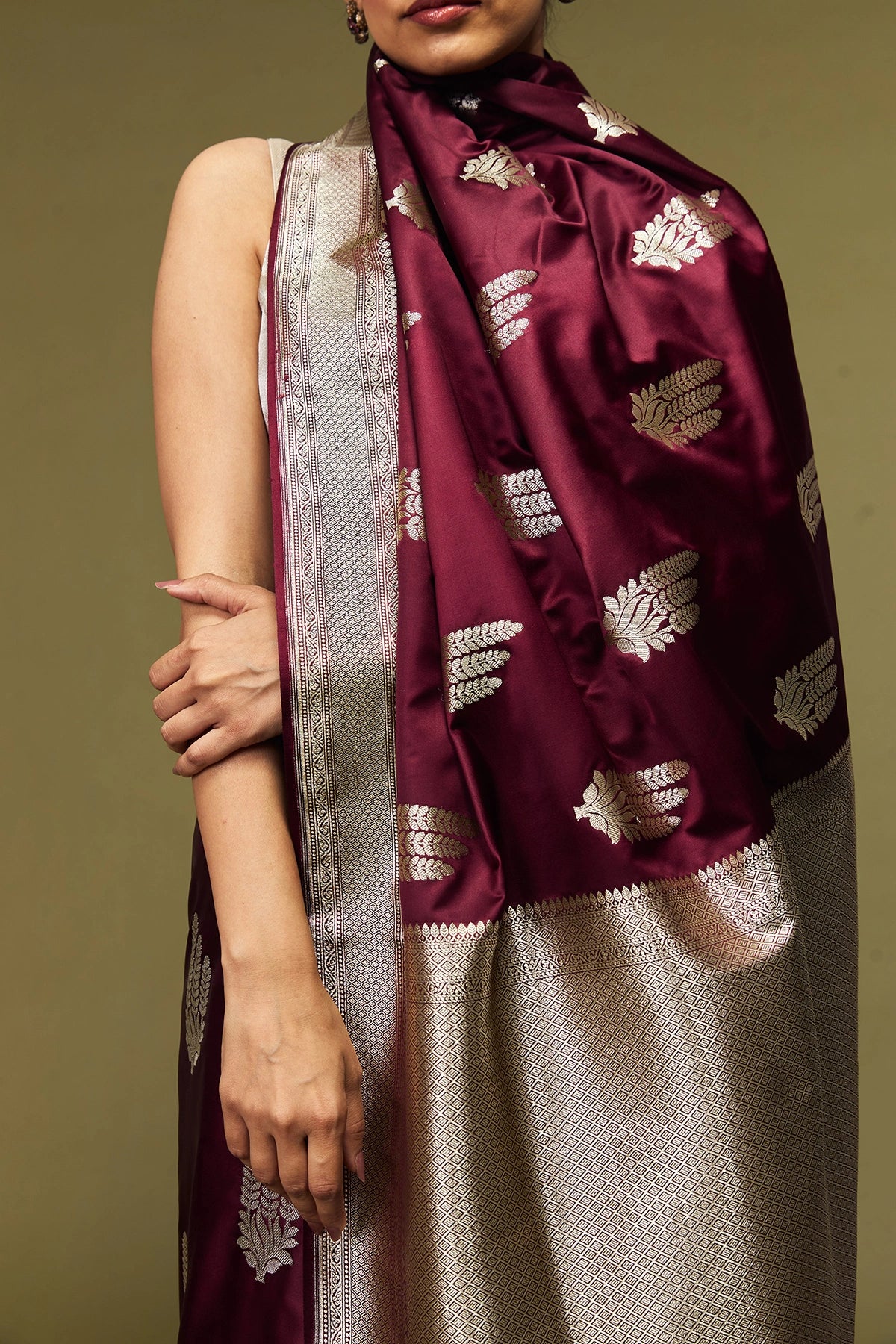 Detailed view of golden floral booti motifs woven across the body of the maroon Banarasi Mashru silk saree.