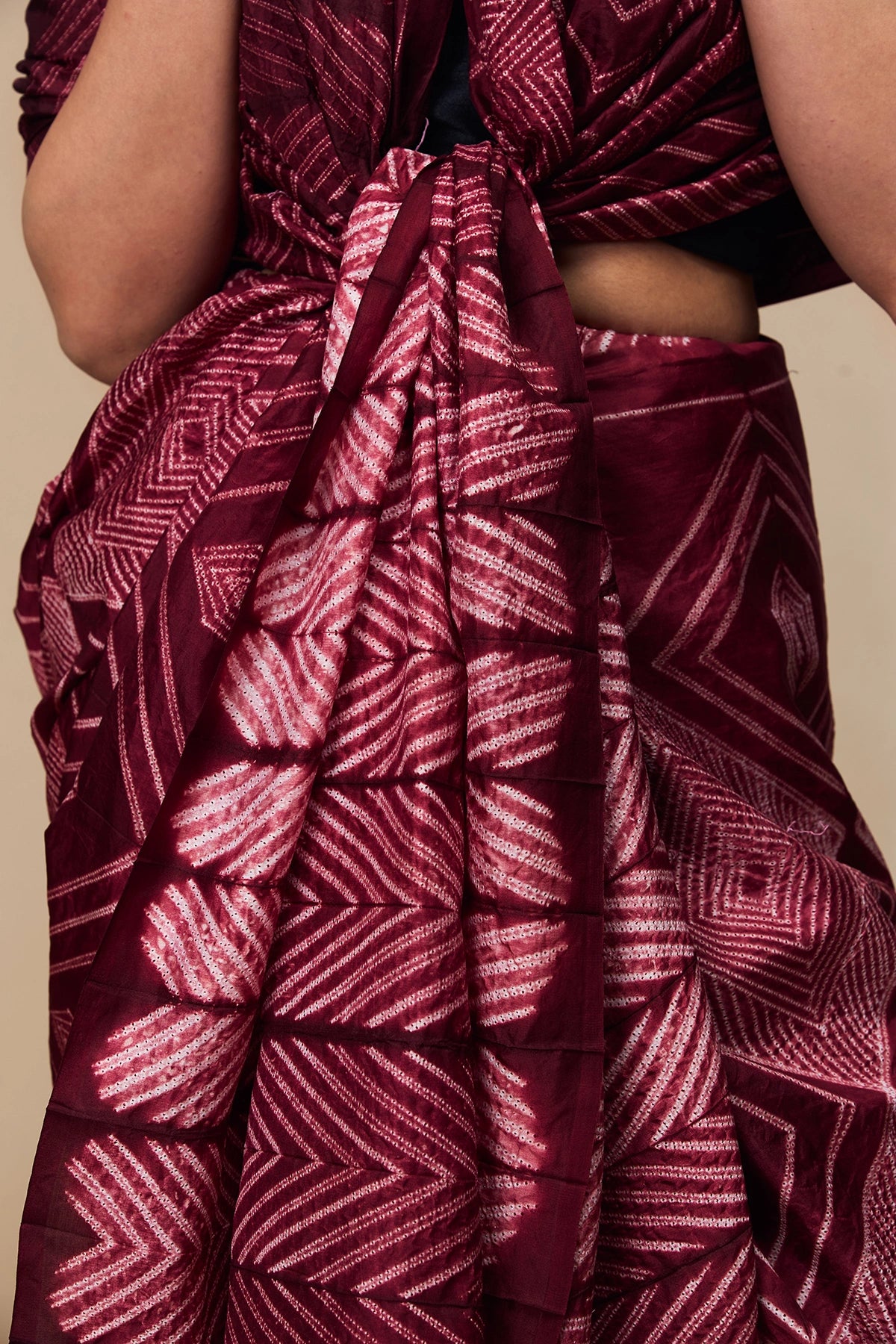 Close-up of concentric Shibori motifs on maroon silk fabric