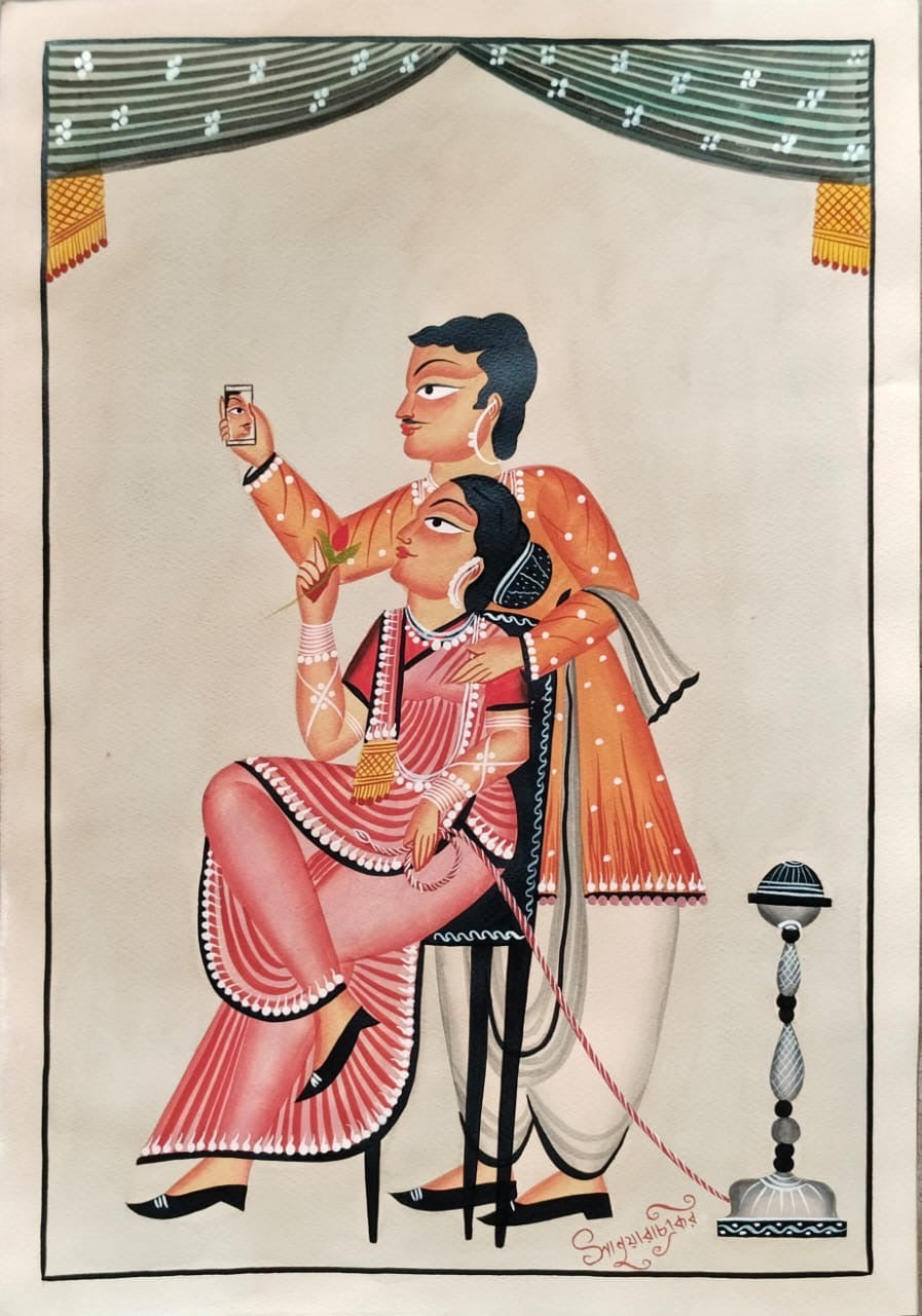 A traditional Indian folk art print depicting a seated woman in a pink and red sari being held by a standing man in an orange patterned kurta. The scene is framed with a decorative border and a small lamp on the right, set against a warm beige background.