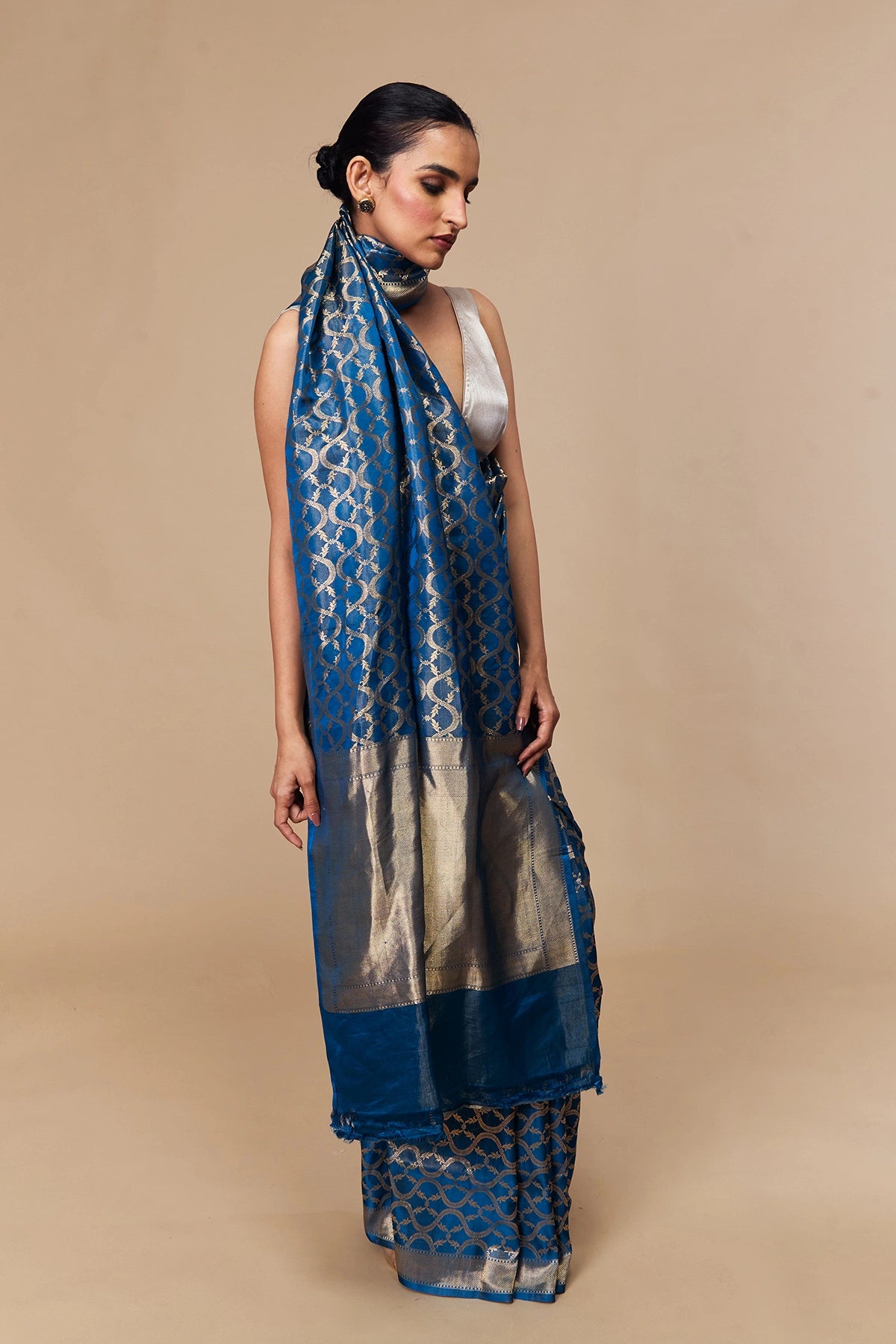 Model draped in azure blue satin tissue Banarasi saree with gold vine motifs