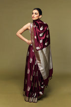 Model wearing a maroon Banarasi Mashru silk saree with golden floral booti motifs, styled with a rich silver zari pallu and border.