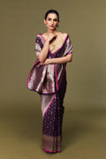 Model draped in handwoven Banarasi Katan silk saree in purple with pink border and golden zari motifs.