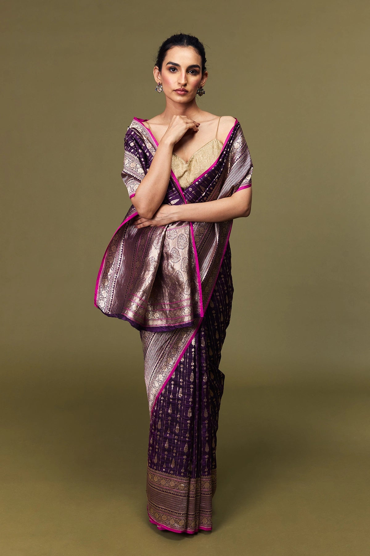 Model draped in handwoven Banarasi Katan silk saree in purple with pink border and golden zari motifs.
