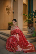 Woman in a red saree sitting on steps indoors